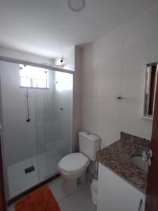 a white bathroom with a toilet and a shower at Férias em Família Apartamento Temporada in Cabo Frio