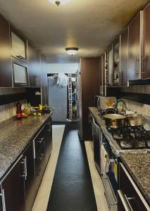 波哥大的住宿－Casa feliz，厨房配有黑色橱柜和长长的走廊