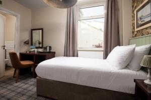 a bedroom with a bed and a desk and a window at The Tynemouth Castle Inn - The Inn Collection Group in Tynemouth