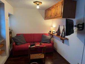 a living room with a red couch and a table at PERLA DI MONTAGNA in Courmayeur