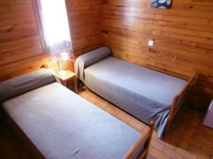 2 Betten in einem Zimmer mit Holzwänden in der Unterkunft La bardane in Brocas