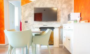een eetkamer met witte stoelen en een televisie aan de muur bij Casa Scotto in Pisa