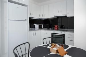 Una cocina con gabinetes blancos y una mesa y sillas. en Art life apartments (cotton), en Alanya