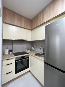 a kitchen with white cabinets and a stainless steel refrigerator at Apartment Romano Banja Luka in Banja Luka