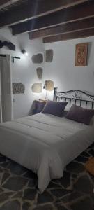 ein Schlafzimmer mit einem großen weißen Bett mit lila Kissen in der Unterkunft Rural Suite Santiago de Tunte in San Bartolomé de Tirajana