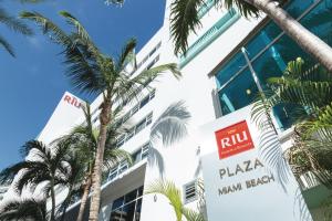 a building with a pizza main break sign and palm trees at Riu Plaza Miami Beach in Miami Beach