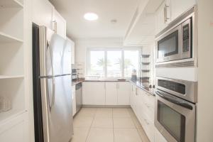 una cocina con armarios blancos y electrodomésticos de acero inoxidable en Maho Beach Suite 2BR Lux Condo next to Morgan Resort en Maho Reef