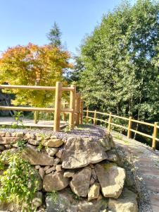 einen Holzzaun und eine Steinmauer im Garten in der Unterkunft Au fil de l'eau in Lapoutroie