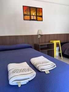 Un dormitorio con una cama azul con toallas. en Reflejos de Luna Llena en Puerto Iguazú