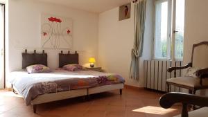 Schlafzimmer mit einem Bett, einem Stuhl und Fenstern in der Unterkunft La masqueria in Montgaillard