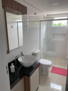a white bathroom with a sink and a toilet at Lindo Apto NOVO na Avenida, climatizado e aconchegante in Piratuba
