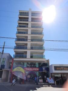 un edificio alto con gente parada frente a él en Lindo Apto NOVO na Avenida, climatizado e aconchegante, en Piratuba