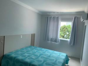 1 dormitorio con cama y ventana en Lindo Apto NOVO na Avenida, climatizado e aconchegante en Piratuba