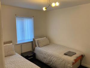 a bedroom with two beds and a window at Spacious 4 Bed House, Sleep 8 Short & Long Stay, Free Parking ,5min Drive from Man City Stadium in Manchester