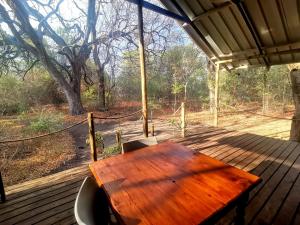 a wooden table on a deck with a view of a forest at The Tshilli Farm & Lodge in Maun