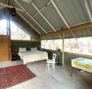 a bedroom with a bed and a table and a chair at The Tshilli Farm & Lodge in Maun