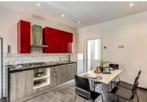 uma cozinha com armários vermelhos e uma mesa com cadeiras em Appartamento dell'acquedotto romano em Roma