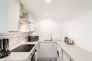 a white kitchen with a sink and a dishwasher at Glasgow City, Hydro Apartment in Glasgow