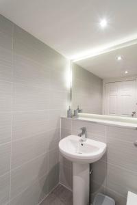 a white bathroom with a sink and a mirror at Glasgow City, Hydro Apartment in Glasgow