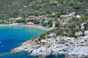 a group of houses on a hill next to the ocean at Hotel Baia Imperiale in Campo nell'Elba