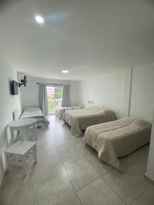 a room with three beds and a table in it at Hotel Los Angeles in Santa Teresita