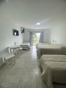 a room with three beds and a table in it at Hotel Los Angeles in Santa Teresita