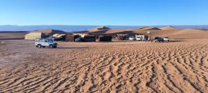 a group of tents and a truck in the desert at Bivouac Les Nomades & Foum zguid to chegaga tours in Foum Zguid