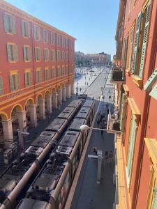 a train traveling down a city street with buildings at Studio Nicehome Massena in Nice