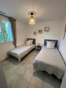 - une chambre avec 2 lits et un lustre dans l'établissement ALLAUCH VILLAGE DE PAGNOL, à Allauch