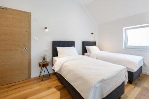 2 camas en una habitación con sábanas blancas en WINERY AND APARTMENTS MAROF, en Bistrica ob Sotli