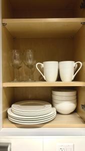 a shelf with plates and cups and wine glasses at Creek Side 2-Bedroom Guest Suite in Burnaby