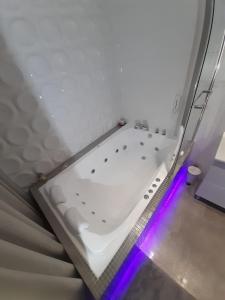 El baño incluye una bañera blanca con luces moradas. en Apartamenty "PRZY KATEDRZE" GORZÓW - jacuzzi, en Gorzów Wielkopolski