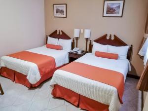 Habitación de hotel con 2 camas con sábanas de color naranja y blanco en Hotel Royal Palace en Guatemala