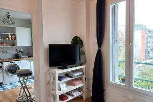 ein Wohnzimmer mit einem TV und einem Fenster in der Unterkunft Cozy studio ideal for a romantic holiday in Montreuil