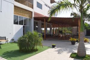 ein Gebäude mit einer Terrasse mit Tischen und einer Palme in der Unterkunft Ohana Beach Hotel in Playas