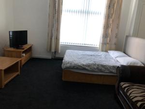 - une chambre avec un lit, une télévision et une fenêtre dans l'établissement Tiffany’s, à Manchester