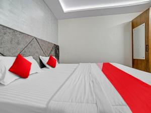 Schlafzimmer mit einem weißen Bett und roten Kissen in der Unterkunft All Seasons Corporate in Jamshedpur