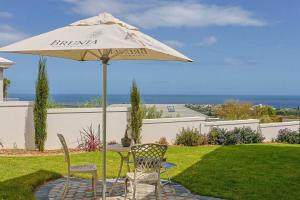 a table and two chairs under an umbrella at The View, Apartment, with magnificent sea view in Hermanus