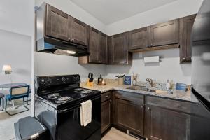 - une cuisine avec des placards en bois et une cuisinière noire dans l'établissement Flexhome Marquette Economy 1BR MP9 - READ INFO, à Milwaukee