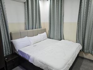 um quarto com uma cama branca e cortinas azuis em HEN - CAP SERVICED APARTMETS em Agege