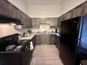 een keuken met houten kasten en een zwarte koelkast bij Flexhome Marquette Economy 2BR MP7 - READ INFO in Milwaukee