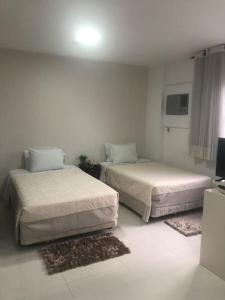 2 camas en una habitación blanca con alfombras en 902Ap em Alphaville maravilhoso en Barueri