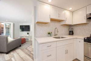 a kitchen with white cabinets and a sink and a couch at Coastal Zen Cottage - Walk To Beach in Half Moon Bay