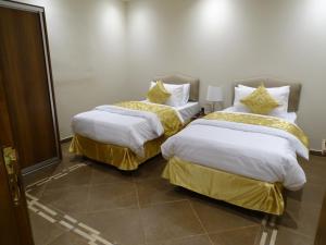 2 camas con mantas blancas y sábanas de oro en una habitación en Comfort Inn Al Taawon - Family Only, en Riad