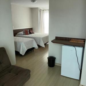 a small room with two beds and a chair at Pousada Souza & Souza in Barra Velha