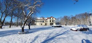 un patio cubierto de nieve con coches aparcados frente a una casa en Willa Biszkoptowa, 