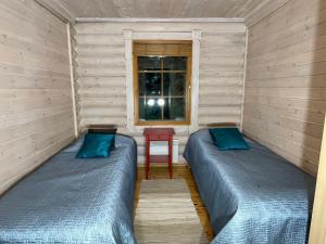 two beds in a room with a window at Villa Saimaa in Vuoriniemi