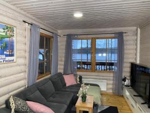 a living room with a couch and a tv at Villa Saimaa in Vuoriniemi