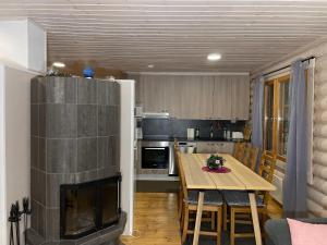 a kitchen and dining room with a fireplace and a table at Villa Saimaa in Vuoriniemi