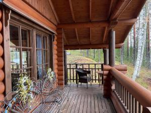 a wooden porch of a log cabin with a chair on it at Villa Saimaa in Vuoriniemi